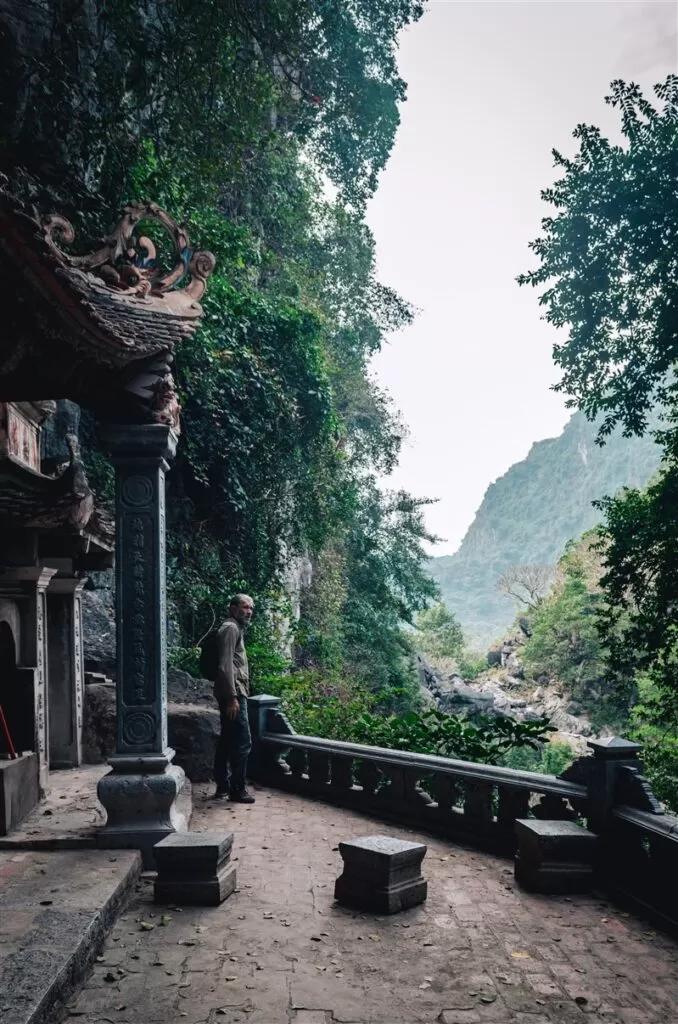 Premium Photo  Lone tourist with traditional vietnamese hat at bich dong  pagoda entrance gate, ninh binh vietnam, buddhist temple set amid jungle  and karst mountain range. traveling alone, keep social distancing.