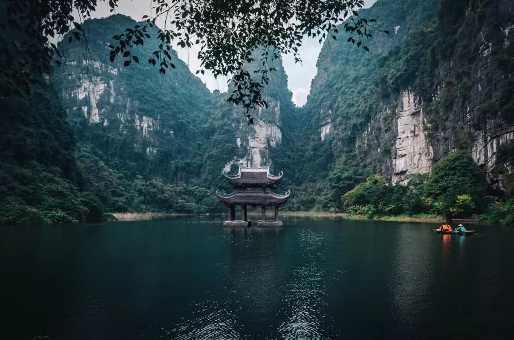 Trang An Scenic landscape Complex is one of the most wonderful places to visit on your north vietnam itinerary. In this photo, you can see a small temple in the water, surrounded by karst mountains in Ninh Binh, Vietnam