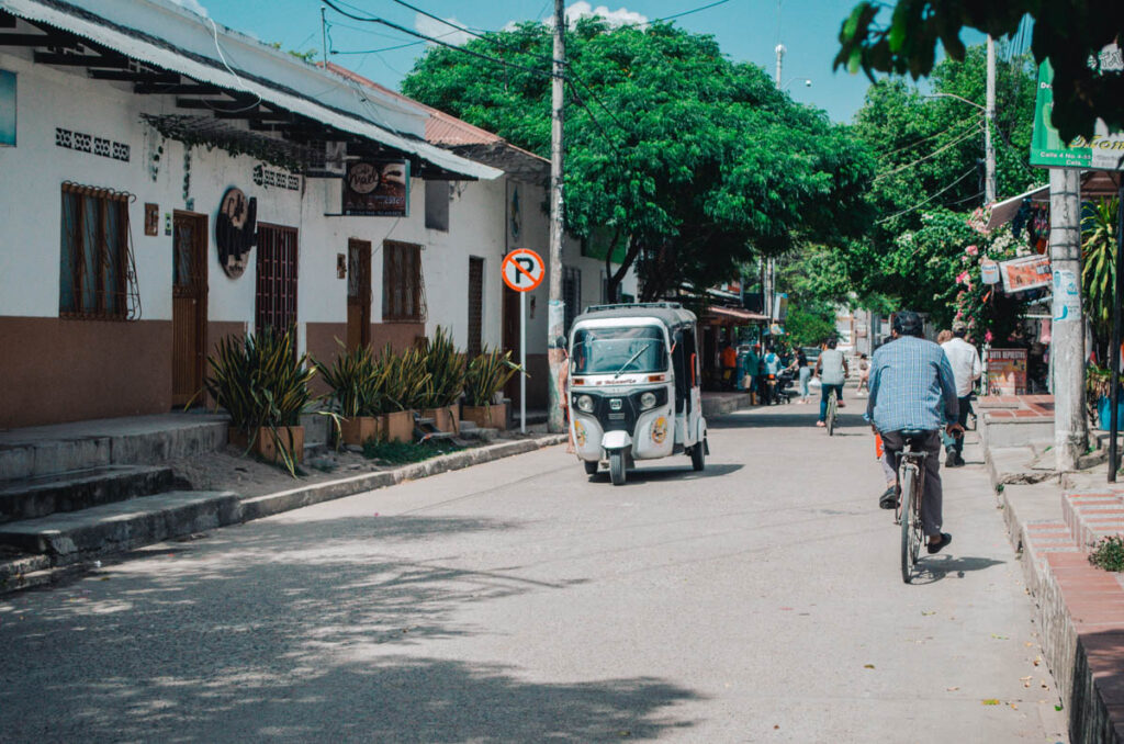 Streets of Villavieja, Colombia. You can see a man on a bicycle and a small tuk-tuk.