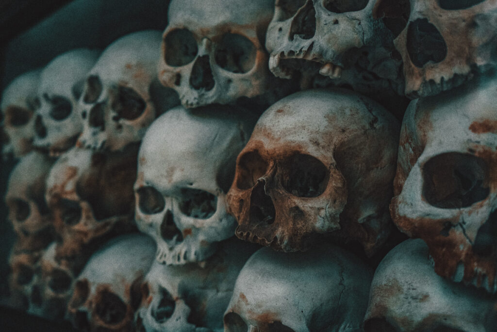 Choeung ek (killing fields), near Phnom Penh, Cambodia: A haunting close-up image of a stack of human skulls, with a dark and moody tone, representing a memorial for lives lost.
