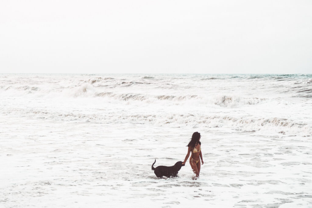 Minca to Palomino- Beach of Palomino, Colombia. A local woman is walking with her dog in the sea.