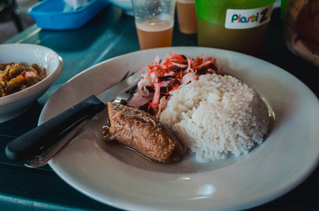 This photo shows a plate of rice, plaintain and beet and cabbage salad with a vegetable stew on the side at a local restaurant in Villavieja in Colombia