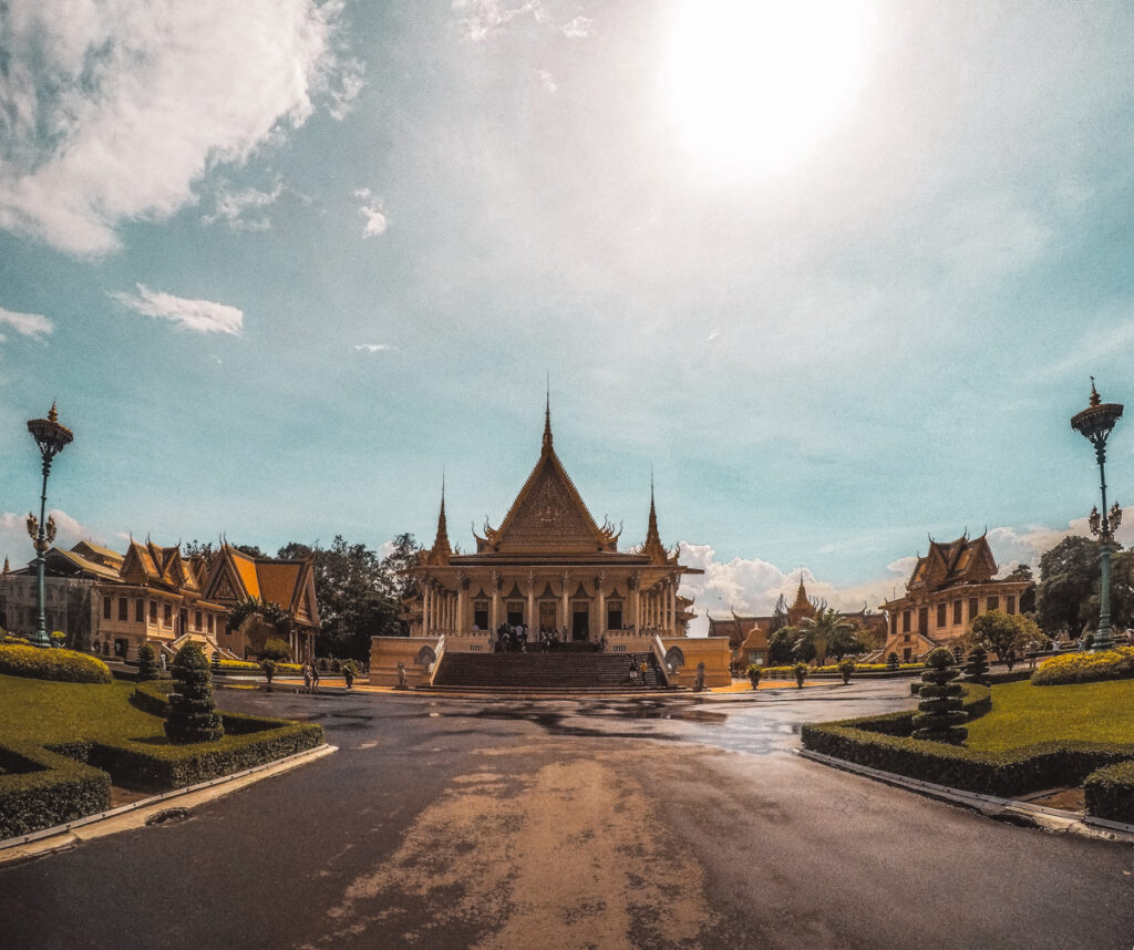 Royal Palace, Phnom Penh, Cambodia: A grand view of the Royal Palace in Phnom Penh, Cambodia, under a bright sun with ornate golden spires and traditional Khmer architectural details.