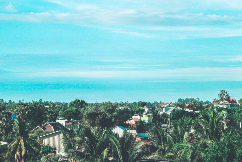 This photo is a View over Siem Reap city in Cambodia. you can see the top of a ffew buildings and lots of greenery.