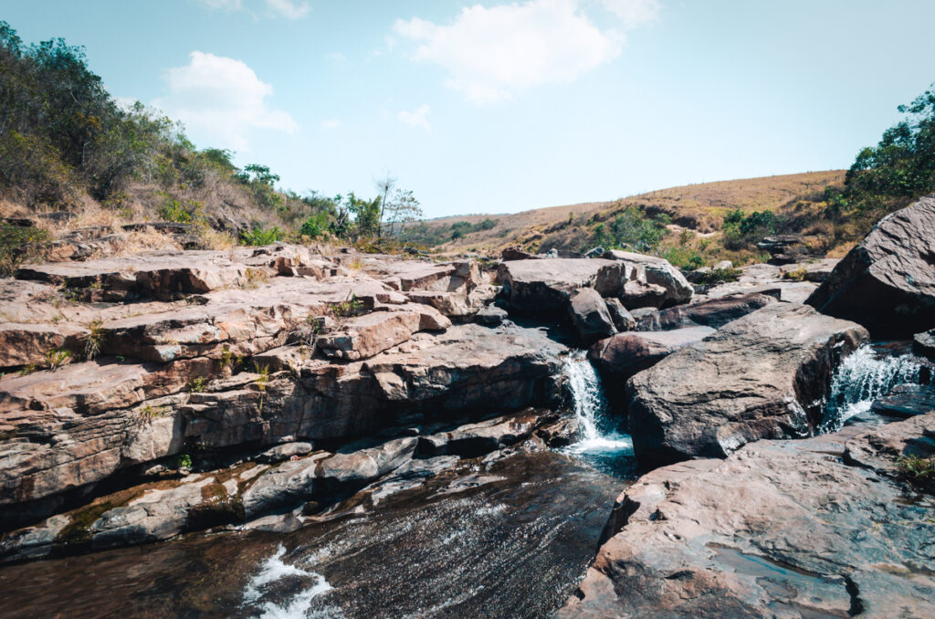 The relaxing vibes of the cascading waters of Pescaderito Curiti, Colombia, surrounded by the region's characteristic rocky terrain under a bright blue sky.
