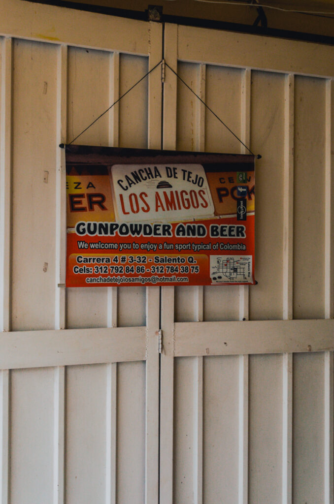 Signage for 'Cancha de Tejo Los Amigos' in Salento, inviting guests to experience gunpowder and beer while enjoying Tejo, a fun sport typical of Colombia.