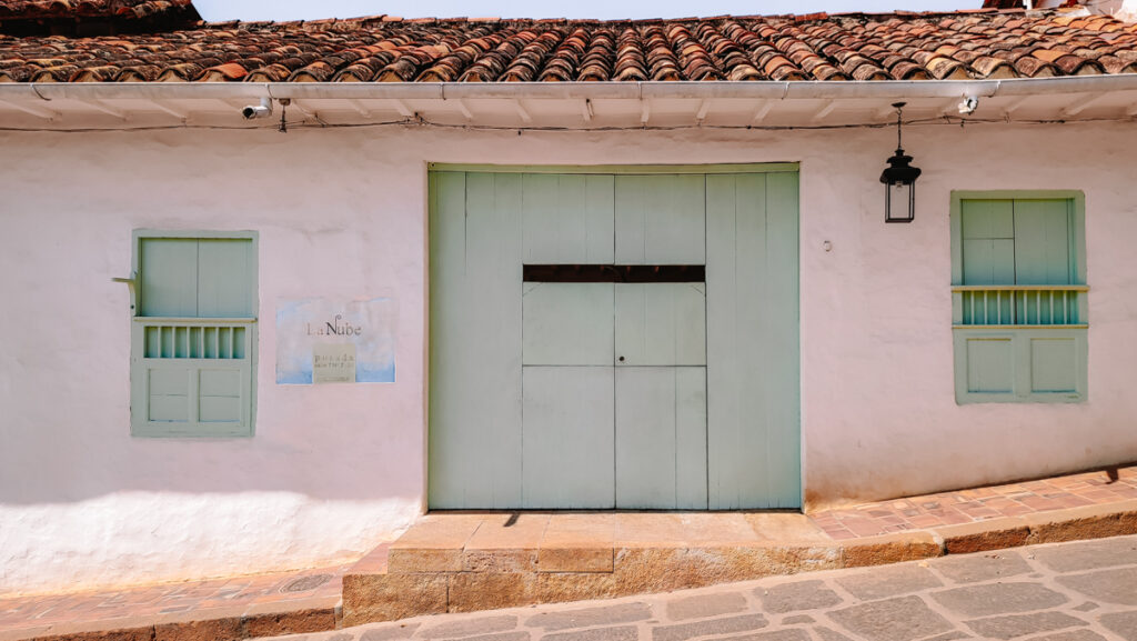 A white building with green shutters, exuding elegance and charm in Barichara, Colombia
