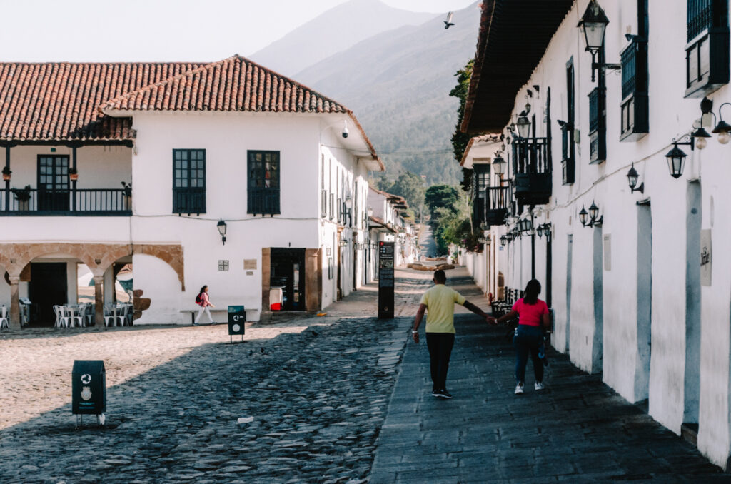 a man and woman walking down a cobblestone street in Villa de Leyva in Colombia